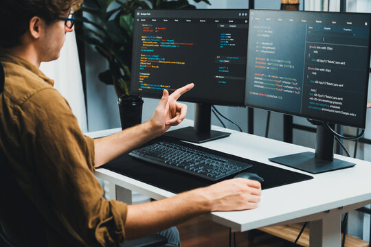 IT developer working online software development on pc monitors at modern home office on coding application screens, creating updated latest program firmware information version concept. Gusher.
