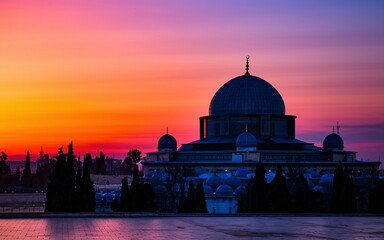 Obraz premium A majestic mosque silhouetted against a vibrant sunrise, creating a breathtaking scene of beauty and spirituality.