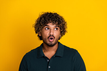 Young man with charismatic expression on vibrant yellow background, showcasing emotion and curiosity, wearing casual black shirt for a modern look.