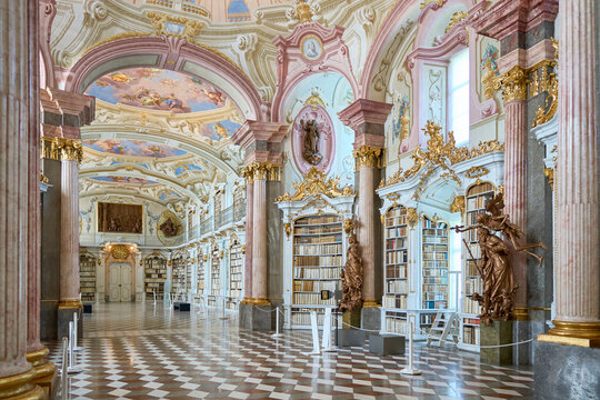 Admont library, Austria, 25 July 2024. A grand baroque library with ornate bookshelves filled with antique books, highlighted by intricate gold detailing