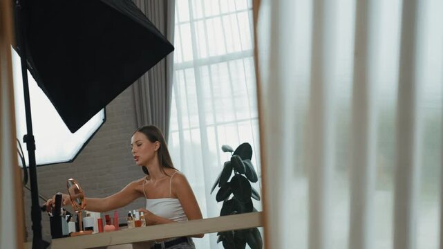 Young beautiful woman making with cosmetic makeup doing hairstyle tutorial video content for social media. Beauty blogger smile to camera while showing how to beauty care to audience or follower. Adit