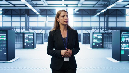 Admin walking in data center, monitoring systems to identify root cause of errors. IT specialist in...