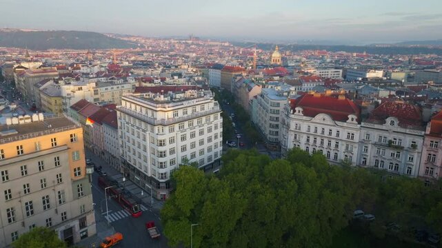 Aerial view of Prague at sunset. The camera pans over a park and buildings, showing the cityscape and the Petrin Hill in the background