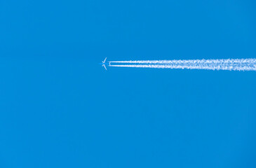 Airplane with Contrails Against Blue Sky
