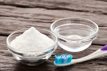 Toothbrush, baking soda and water for oral hygiene - Wooden background.