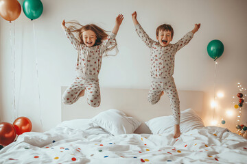 Two happy children wearing pajamas are jumping on the bed in a brightly decorated bedroom