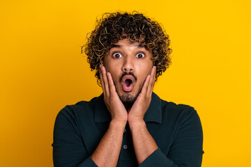 Young man in black shirt against vibrant yellow background express shock surprise with wide eyes...
