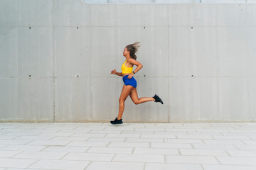 Young sporty woman running in the city wearing fitness tracker