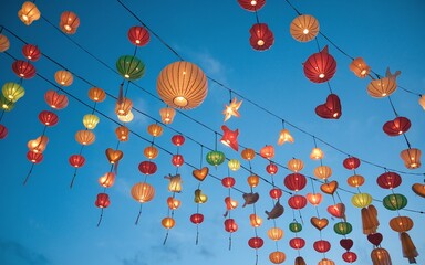 Colorful lanterns hang in the evening sky, creating a festive atmosphere.