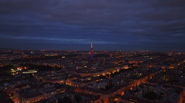 Aerial view of the city of Prague at dusk with clouds moving in the sky. The Zizkov Television Tower stands on the city's skyline