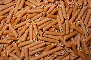 Uncooked Whole Grain Penne Rigate Pasta: A Culinary Canvas of Whole Wheat Macaroni, Creating a Lively and Textured Background for Gourmet Cooking. Whole Grain Dry Pasta. Whole Wheat Raw Macaroni