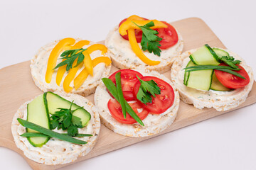 Different Vegan Rice Cake Sandwiches with Fresh Tomato, Yellow Paprika and Greens on Wooden Cutting Board. Vegetarian Diet Food. Quick and Healthy Sandwiches. Crispbread with Fresh Fillings