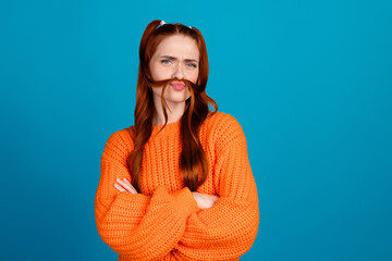 Fototapeta premium Photo of doubtful lovely girl orange knitwear sweater making tails fake mustache looking empty space isolated blue color background