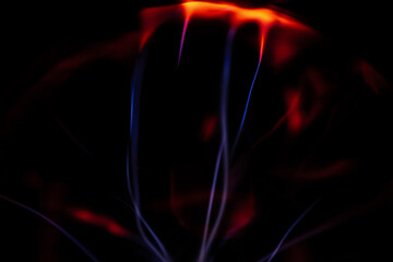 A glowing plasma ball with red and blue energy arcs radiating against a dark background, creating a vivid and electrifying visual effect