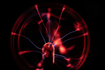A plasma ball radiating red and blue electric arcs from its center, creating a vibrant and mesmerizing visual effect against a dark background