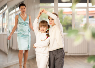 Boy with girl during contemporary dancing lesson. Children in sport wear rehearse rumba movement....
