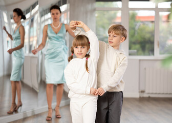 Small passionate ballroom enthusiasts, tween girl and boy practicing graceful waltz routine in...