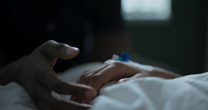 Hands with catheter on hospital white blanket.