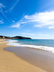 Sandy beach and sea whith whispy white clouds