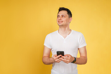 A man wearing a crisp white shirt is holding a cell phone securely in his hands as he engages with the device