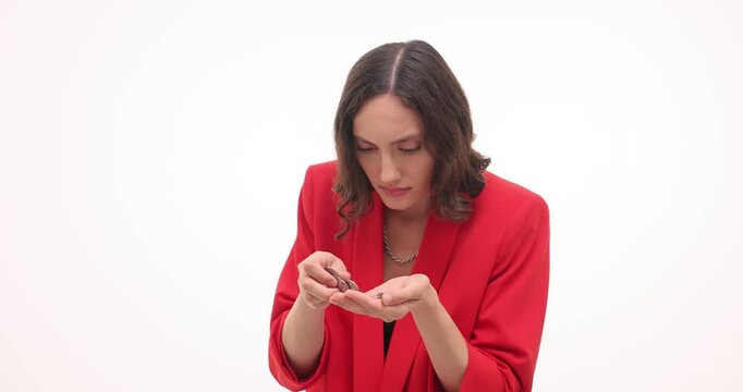 Greedy businesswoman in red blazer coins coins in palm on white background. Emotional female hides cash money in hand turning around slow motion