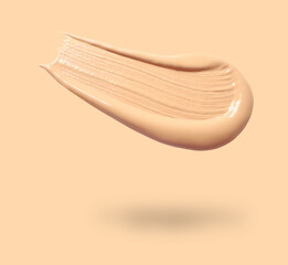 Skin foundation in air on beige background. Cosmetic product