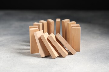 Domino effect. Wooden blocks falling on grey table, closeup