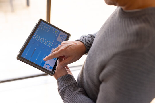 Asian senior man using tablet to control smart home devices, adjusting settings easily