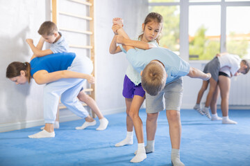Obraz premium Children boy and girl partner in sparring practice technique practicing basic attacking movements and maneuvers. Class self-defense training in presence of experienced instructor