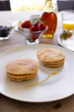 Pancakes with syrup and fresh fruit on breakfast table, ready to enjoy, at home