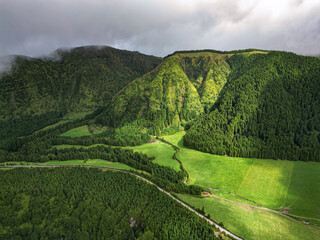 Aerial drone view of a beautiful green mountain landscape. Tranquil valley, dark clouds, fields, forest and road. Sete Cidades, Sao Miguel Island, Azores, Portuga