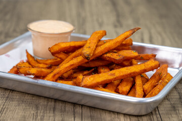 Crispy order of sweet potato french fries on a tray with hot mustard dipping sauce