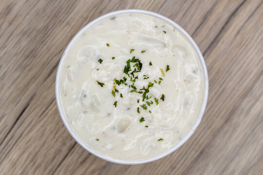 Overhead view of creamy bowl of hot clam chowder topped with parsley for a soothing soup to eat