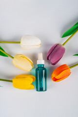 Cosmetic product in tube, bottle, lotion or serum with stylish props and colorful tulips on white background. 