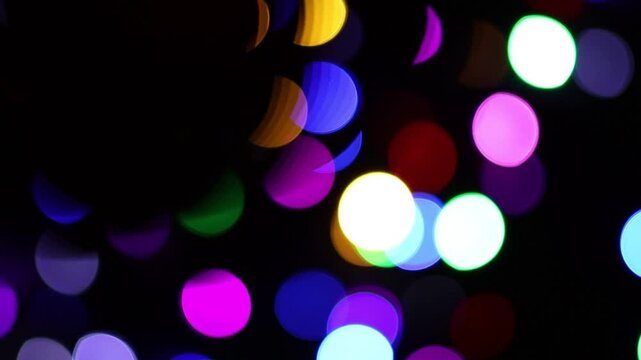 Una toma de cerca una sombra de una bola de navidad roja rodeada de luces de varios colores con un fondo desenfocado.  Decoraci&oacute;n de navidad y fin de a&ntilde;o