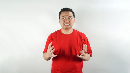 Naklejka premium A young Indonesian man wearing a red t-shirt with an angry face facing forward