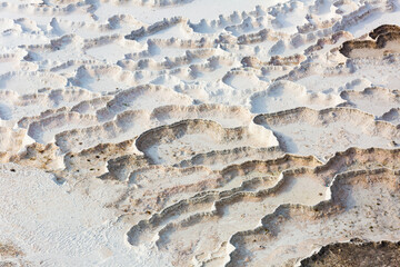 Lacy white travertine formations at hot springs of cotton castle of Pamukkale on sunny day, Turkey
