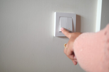 A finger turning on lighting switch .