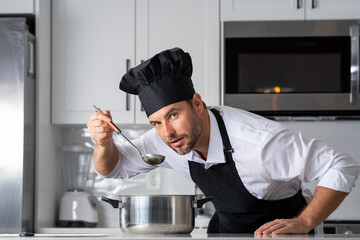 modern chef in professional uniform. close-up on the hand of male chef who is stirring soup in pot with spoon. cooking, culinary and people concept - male chef in toque with pot or saucepan.