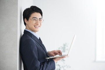 士業や税理士、コンサルタントなどのイメージ　パソコンを持つ　カメラ目線