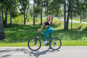 Obraz premium Caucasian woman riding a bike in a park. Vertical photo. 