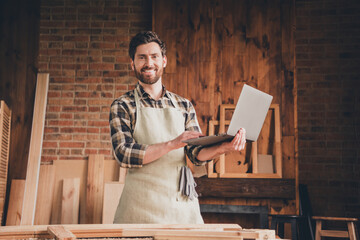 Photo of happy guy professional workman standing using netbook in garage workshop