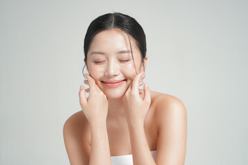 グレー背景で撮影をした若いアジア女性のスタイリッシュなスキンケアイメージ © Hidden Stitch