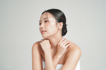 グレー背景で撮影をした若いアジア女性のスタイリッシュなスキンケアイメージ © Hidden Stitch