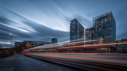 Fototapeta premium A cityscape at dusk with modern buildings and light trails from passing vehicles.