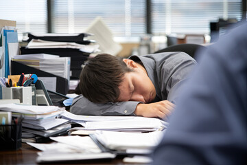 An exhausted employee falling asleep at their desk, with work still to be done