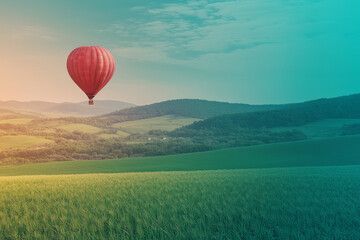 Fototapeta premium Red Hot Air Balloon Soaring Over Lush Green Landscape