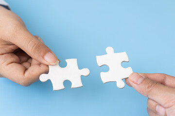 Business team holding parts of jigsaw puzzle trying to find solution to problem together.  Concept of challenge and determination as the person works to complete the puzzle.