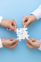 Business team holding parts of jigsaw puzzle trying to find solution to problem together.  Concept...