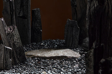 A plate rock with a blank surface in the center is encircled by charcoal blocks on a warm brown...